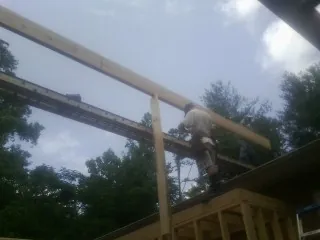 Carpenter setting a ridge beam over a new addition frame — Ice Dam Removal by Roofing Brothers in Coralville