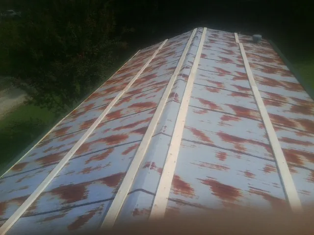 Rusted metal roof panels with new wood purlins before replacement — Storm Damage Roof Repair in Coralville by Roofing Brothers