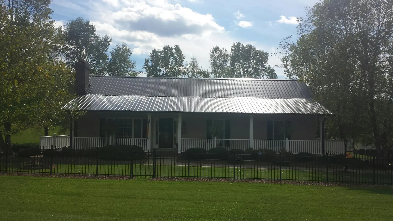 Gray metal roof on a brick ranch with a full width front porch — Gutter Guard Installation work by our crew in Coralville