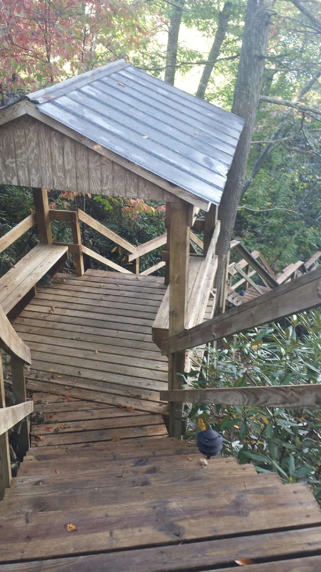 Metal roofed shelter over wooden steps on a wooded walkway — Skylight Repair & Installation work by our crew in Coralville