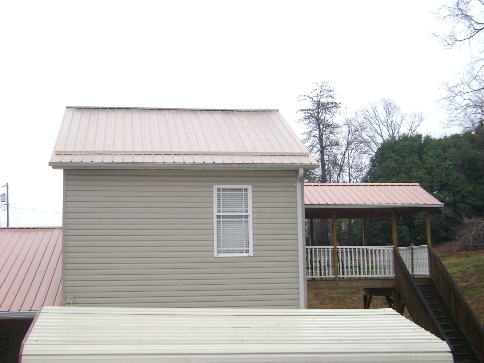 Tan metal roofs on a two story addition and attached porch, from a Roof Replacement job in Coralville